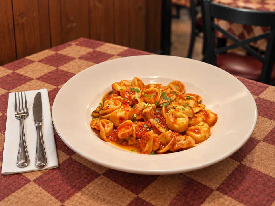 Filled pasta with red sauce on Gumba’s patterned table. AI-assisted image.